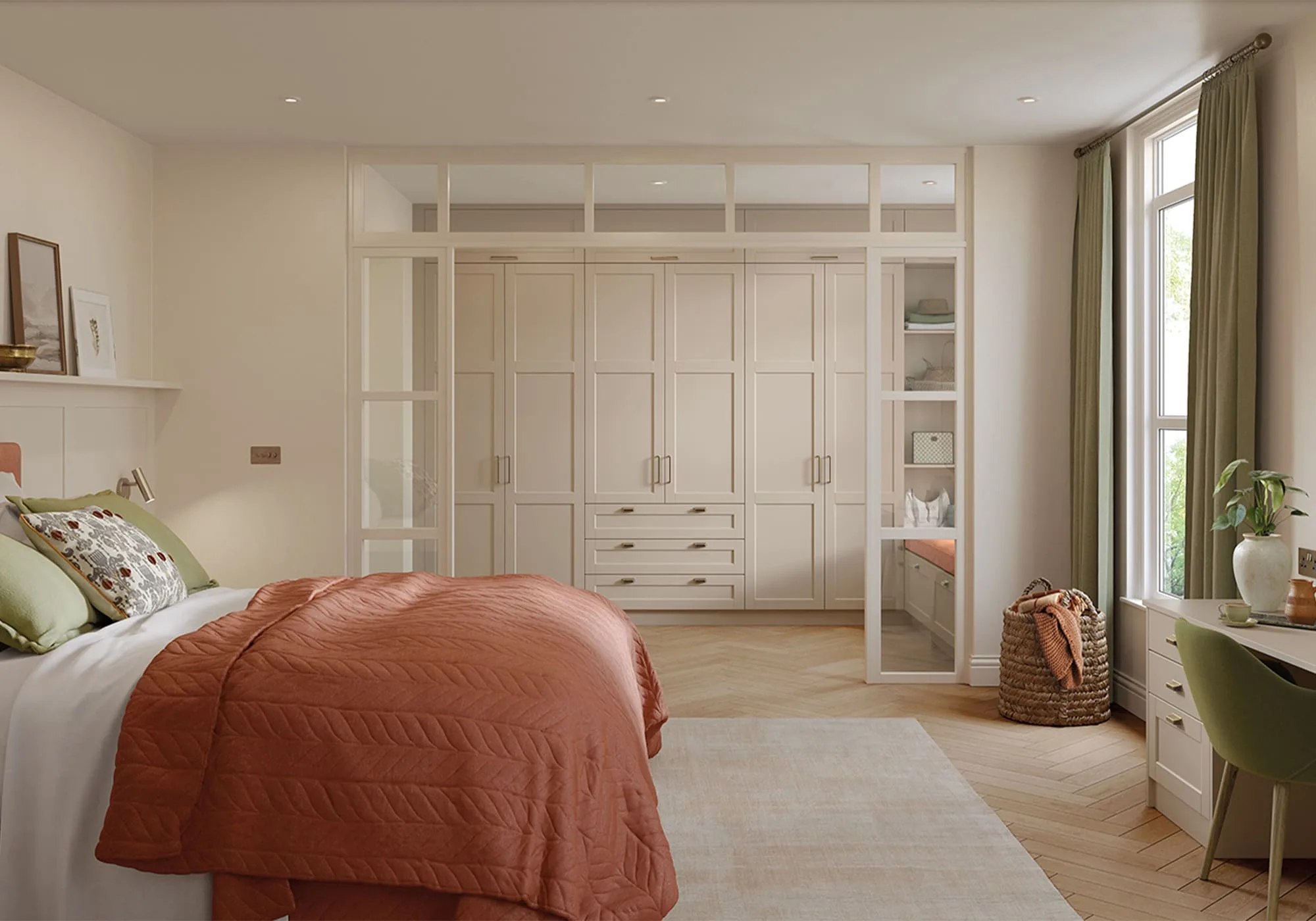 Cream fitted wardrobes with brass handles and a glazed dressing room partition in a bespoke bedroom