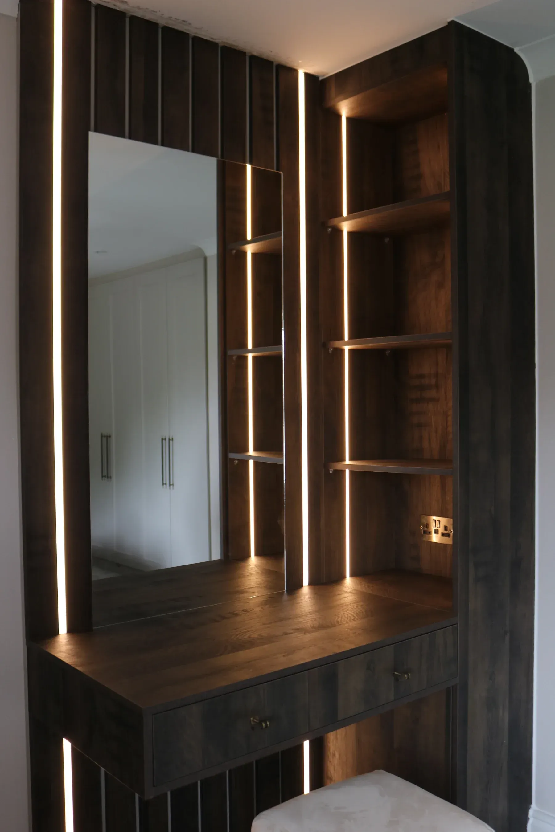 Dark wood dressing corner with LED-lit mirror and shelves, real installation